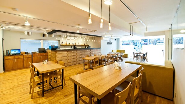 En moderne restaurant med træborde og stole, et køkkenområde og en bar.