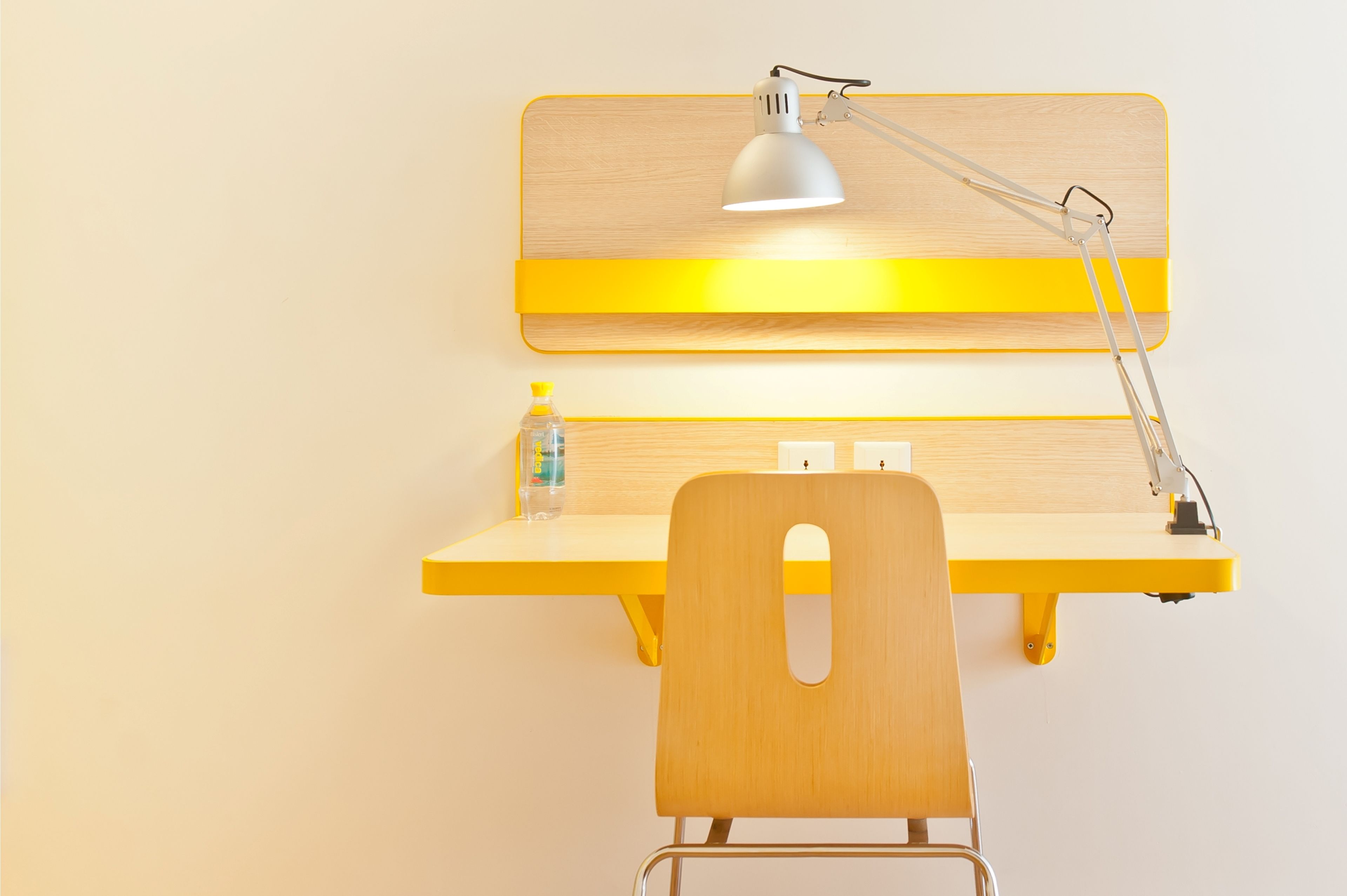 A workspace with a desk, chair, lamp, and a bottle of water.