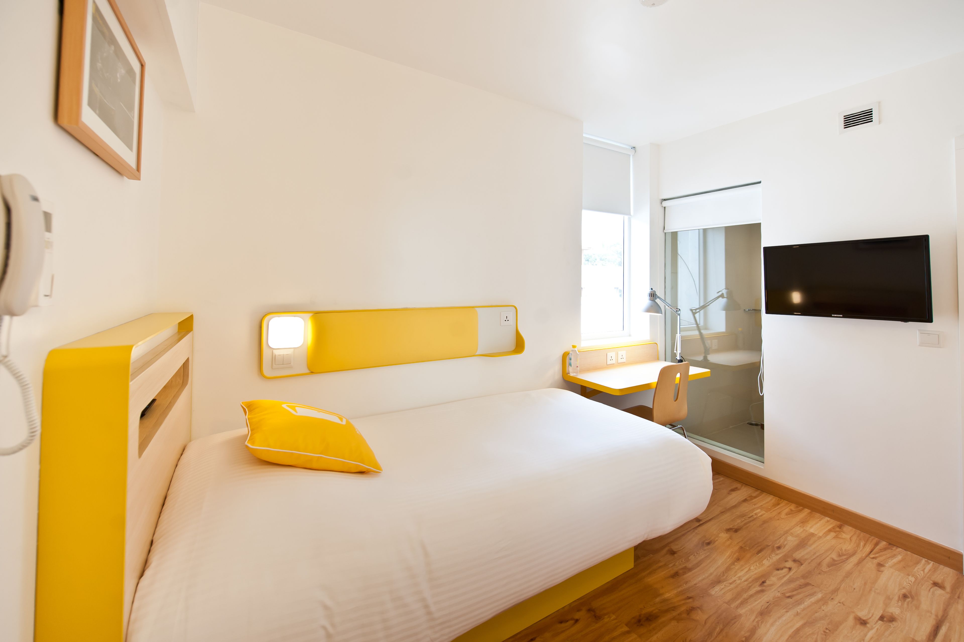Habitación de hotel con cama, escritorio, silla, televisor y ventana.