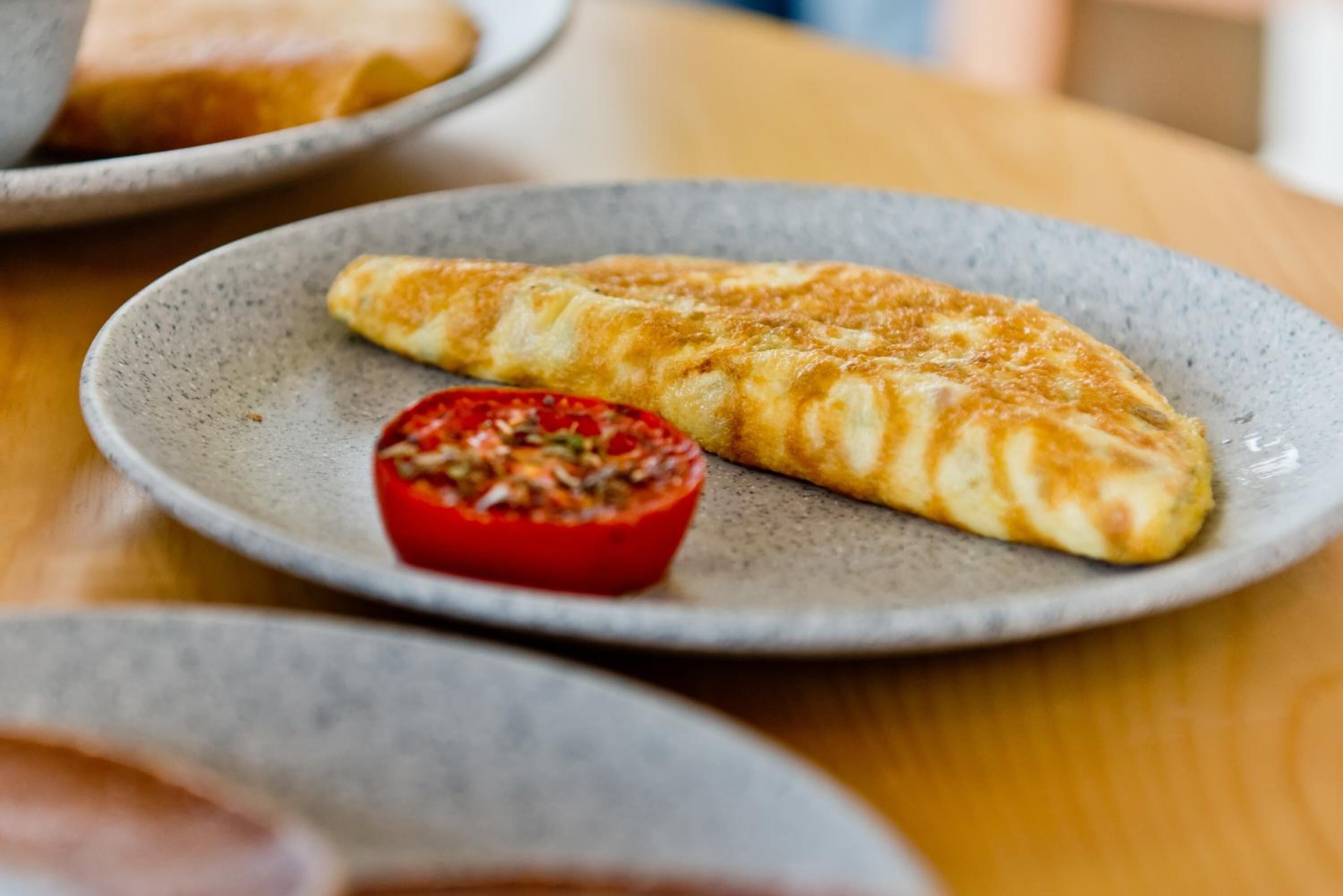 Un plato con una tortilla francesa doblada y un recipiente pequeño con salsa de tomate.