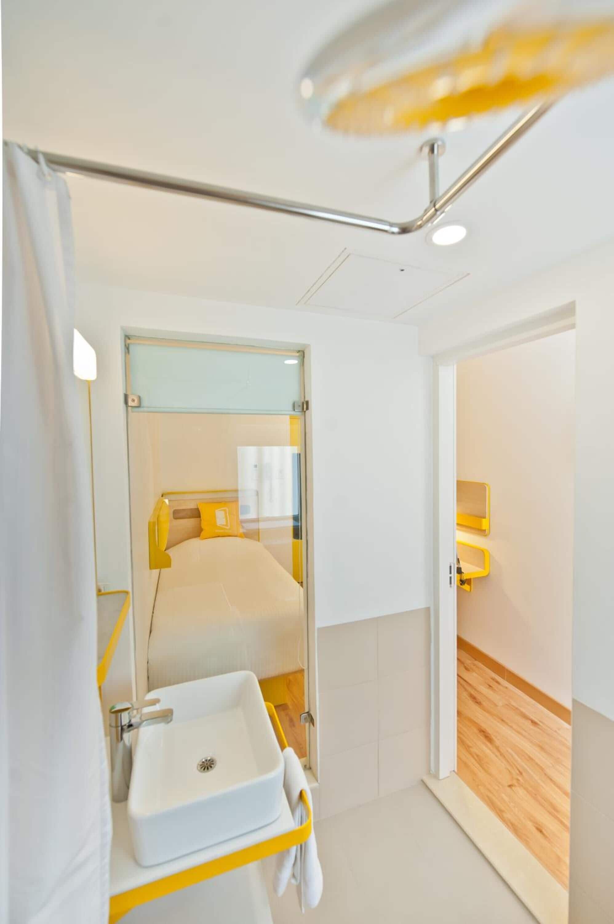 A modern hotel room with a bed, a white sink, and a mirror.