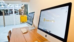 Et moderne kontor med et træbord, en stationær computer og en gul kuffert.