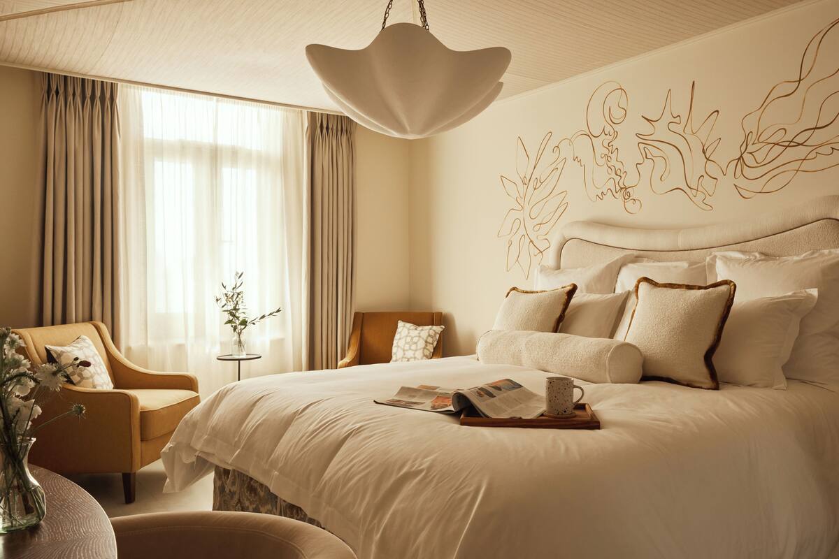 Ett modernt hotellrum med en stor säng, en sittgrupp med en fåtölj och en dekorativ väggdekoration.