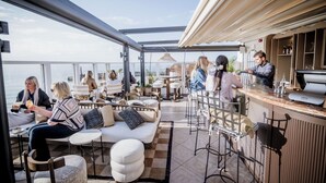 An outdoor seating area with a bar, cushioned seating, and a view of the sea. - No.42 by GuestHouse Margate (Margate)