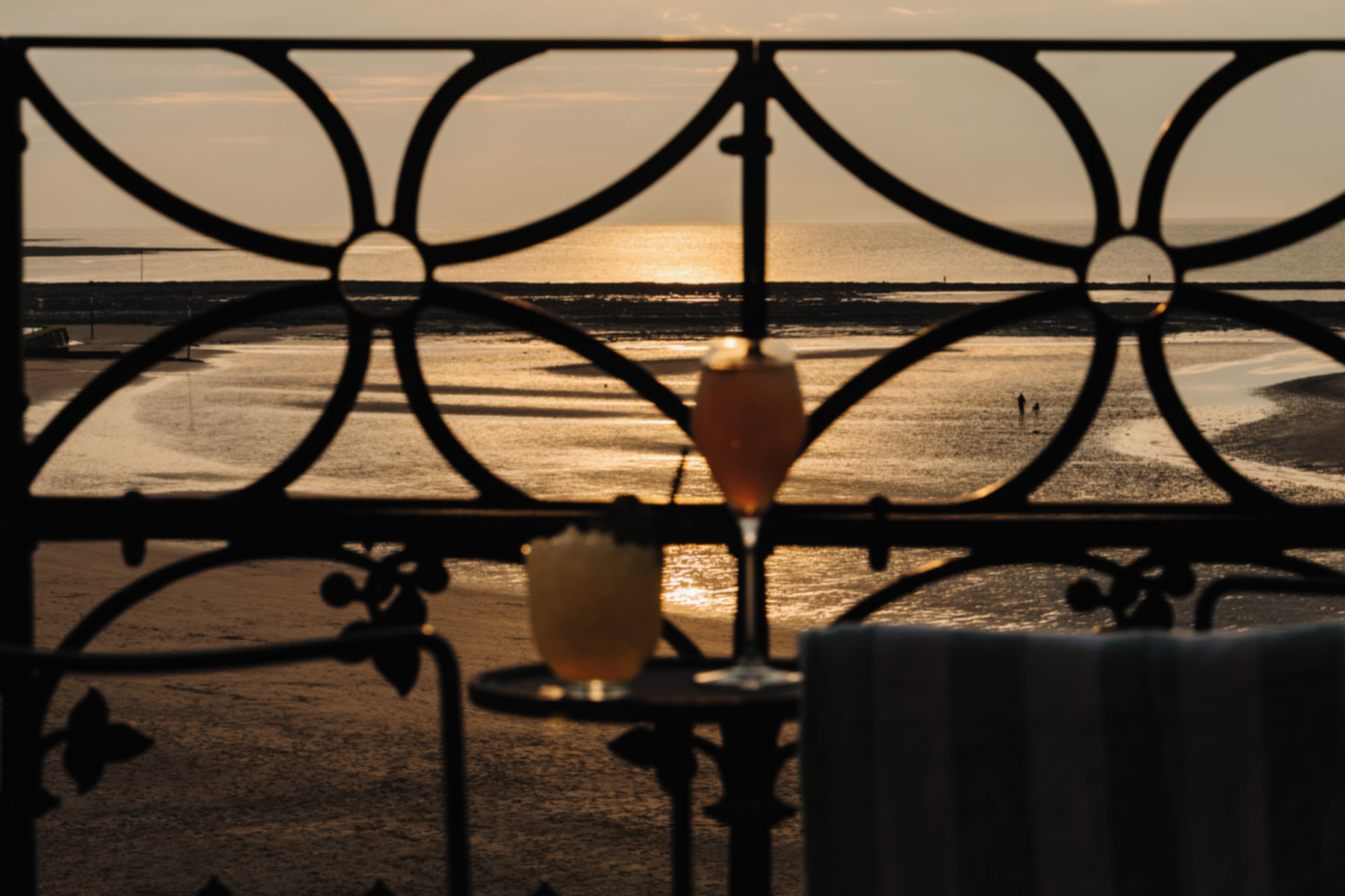 Un balcon avec vue sur la plage et l’océan au coucher du soleil.