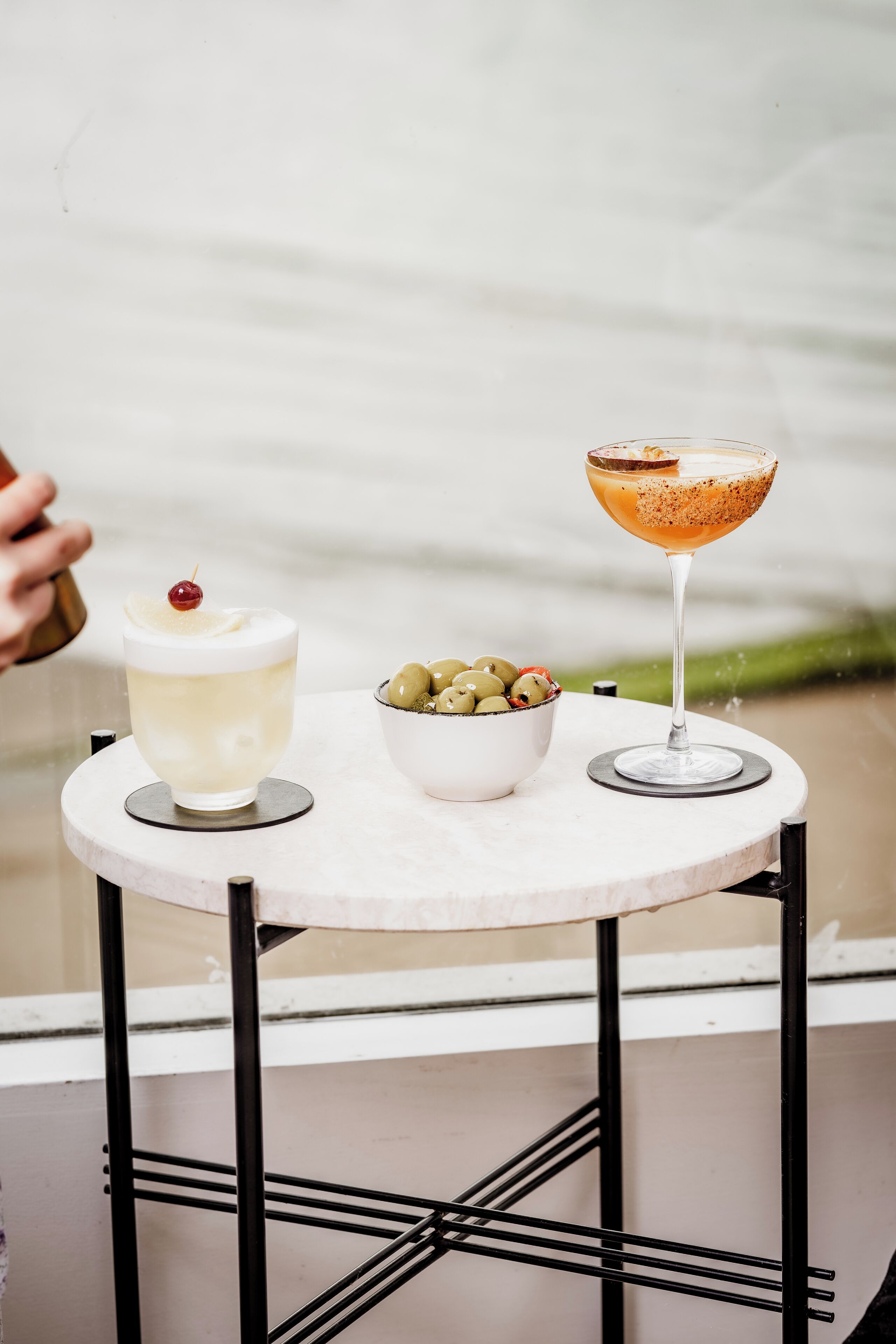 A table with two drinks and a bowl of olives.