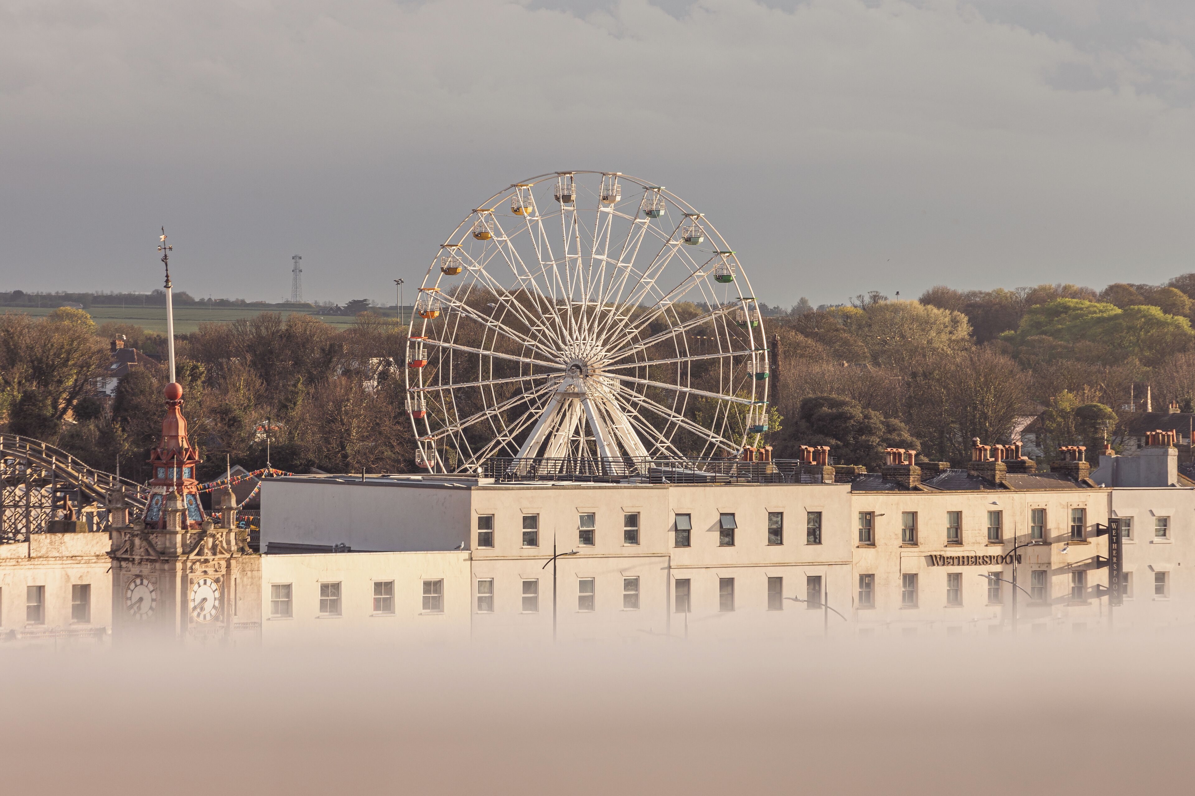 Ein großes Riesenrad mit einem Gebäude im Vordergrund.