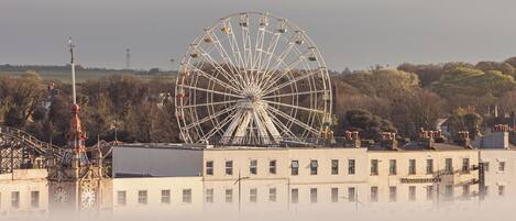 A large Ferris wheel with a building in the foreground.