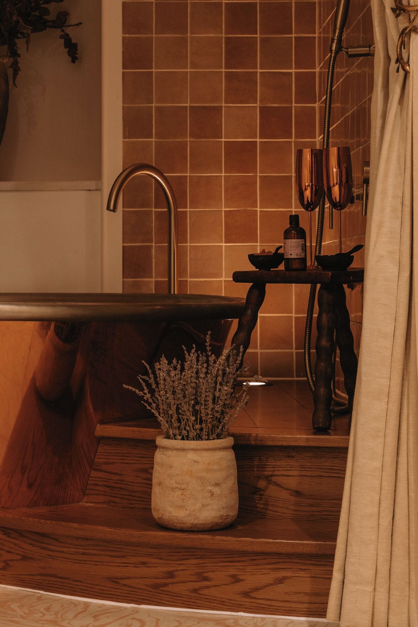 Une salle de bain avec un meuble-lavabo en bois, un pot de lavande et un espace douche équipé d’un porte-serviettes.