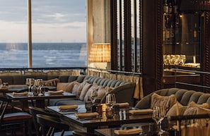 A restaurant with a view of the sea, featuring a bar area with bottles and glasses, and a seating area with tables and chairs. - No.42 by GuestHouse Margate (Margate)