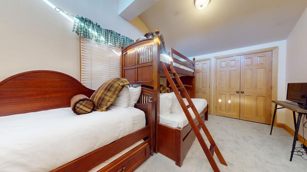 Une chambre avec un lit superposé, un bureau et une armoire.