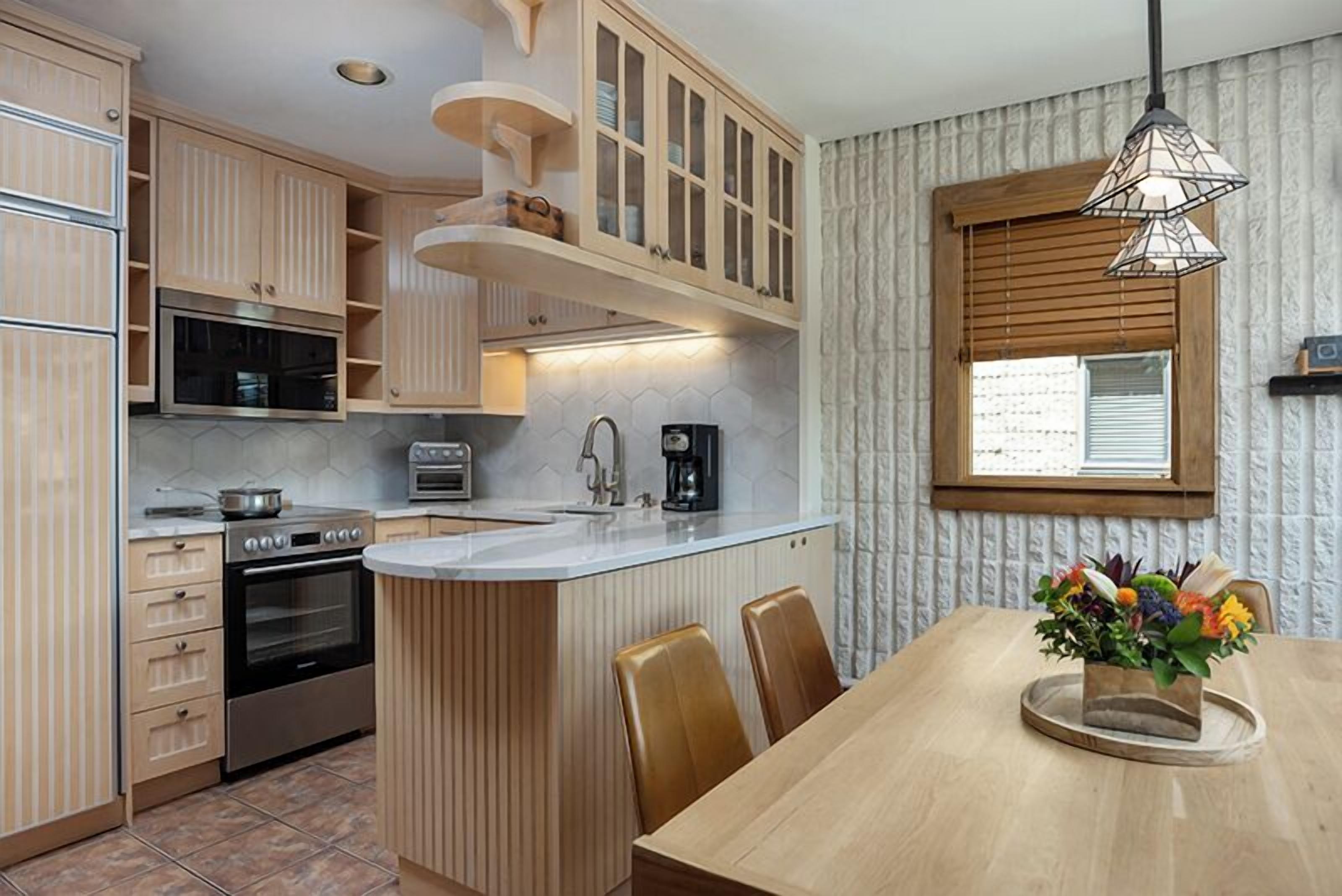 Een keuken met houten kastjes, een ingebouwde oven, een magnetron en een koffiezetapparaat.