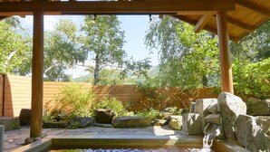 A wooden pergola over a koi pond with a waterfall, surrounded by rocks and greenery. - Pension Asanebou (Minakami)