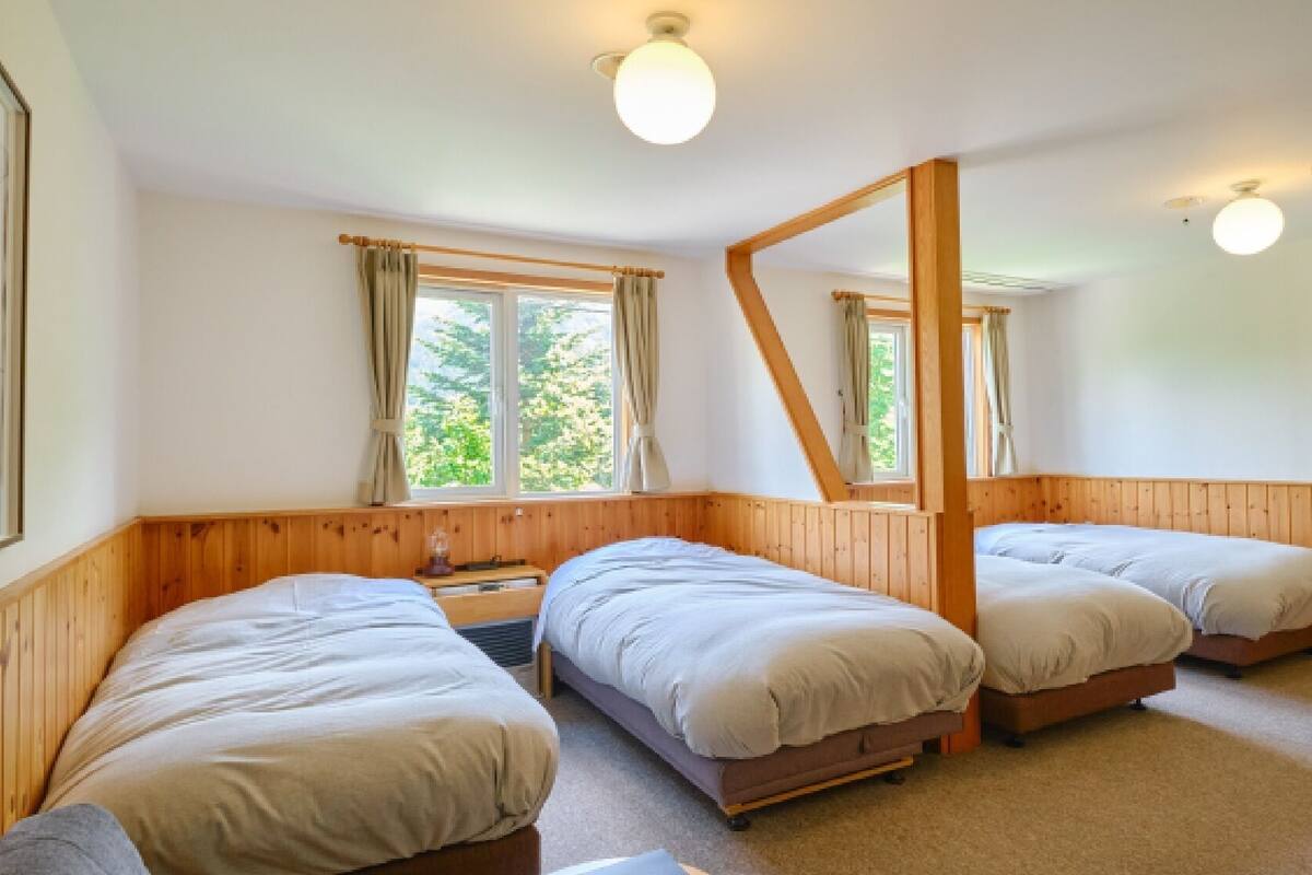 A room with three wooden beds, a wooden ceiling, and a large mirror.