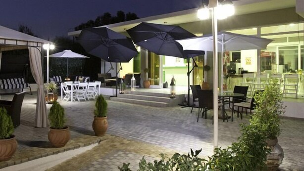 Un espace extérieur aménagé en terrasse, avec un coin salon couvert, des tables et des parasols.