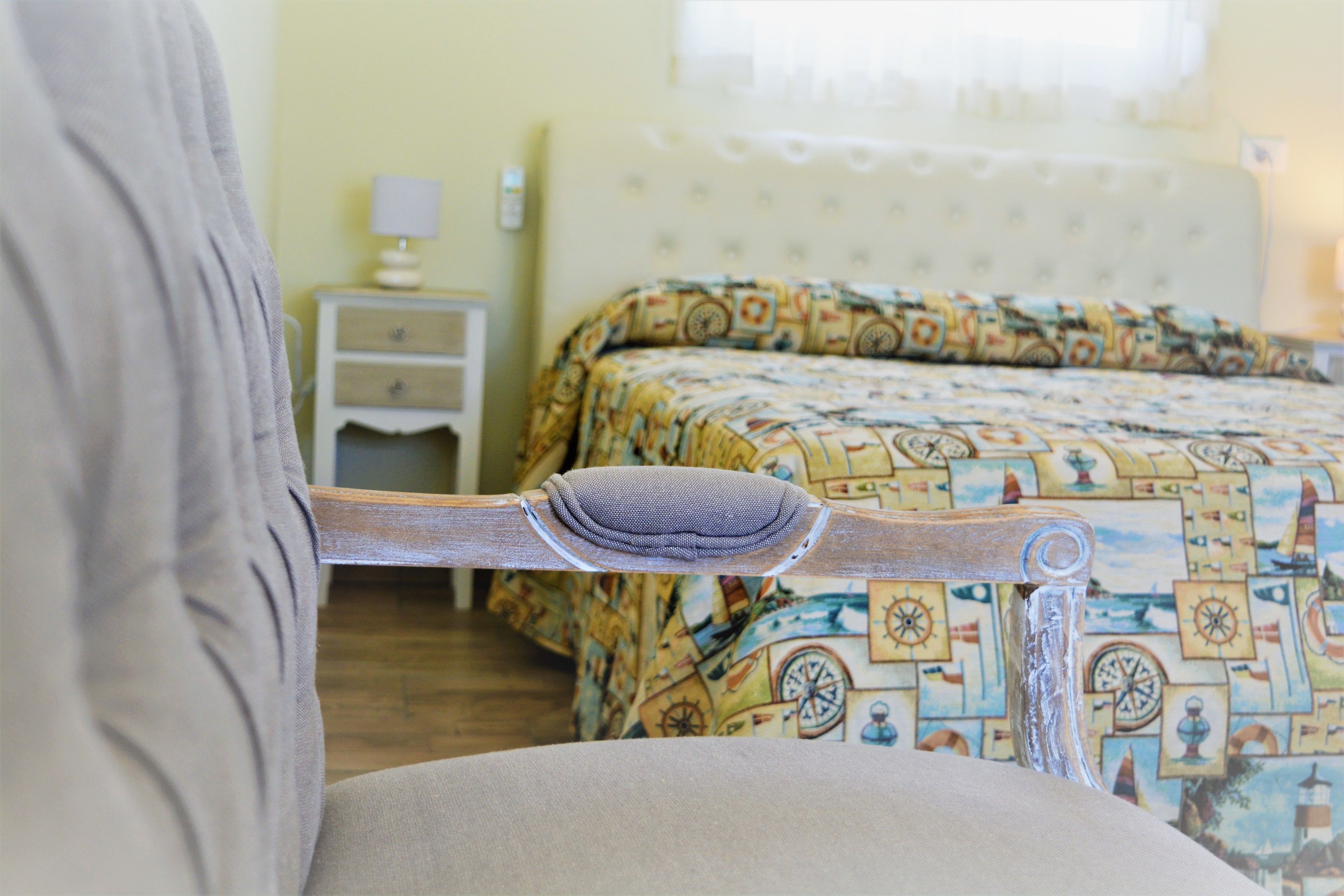 Una cama con colcha estampada, cabecero de madera y mesita de noche con lámpara.