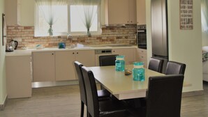 Une cuisine moderne avec un coin repas, comprenant un îlot de cuisine, un réfrigérateur et une table à manger avec des chaises.