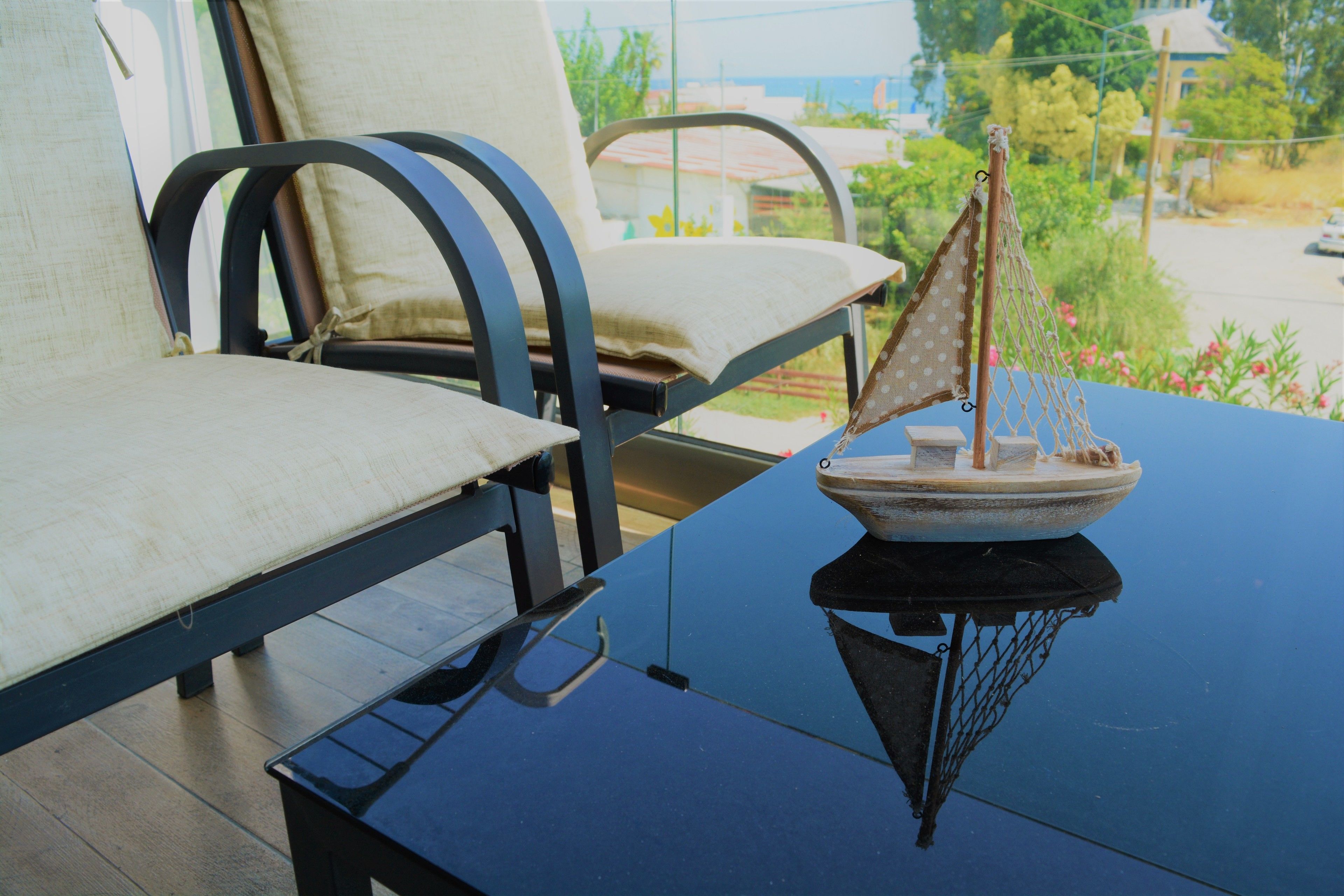 A room with a blue table, two chairs with cushions, and a small sailboat model on the table.
