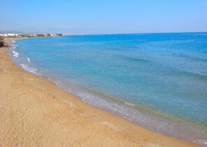 Une plage avec une eau d’un bleu limpide et un rivage sablonneux.