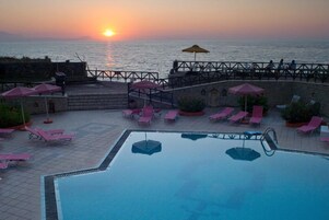 Una piscina al aire libre de temporada, sombrillas, tumbonas