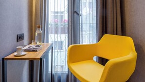 A room with a yellow chair, a small table with a cup and a laptop, and a window with curtains. - Lampa Design Hotel - Special Class (Istanbul)