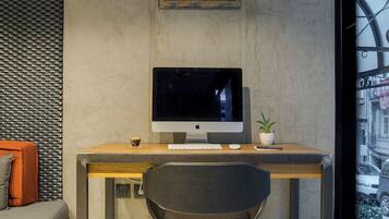 A modern office space with a desk, computer, chair, and decorative wall piece.