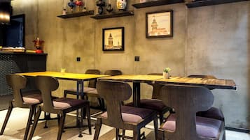 Uma área de refeições moderna com uma mesa comprida e cadeiras, uma parede de concreto com objetos decorativos e uma moldura com uma imagem.