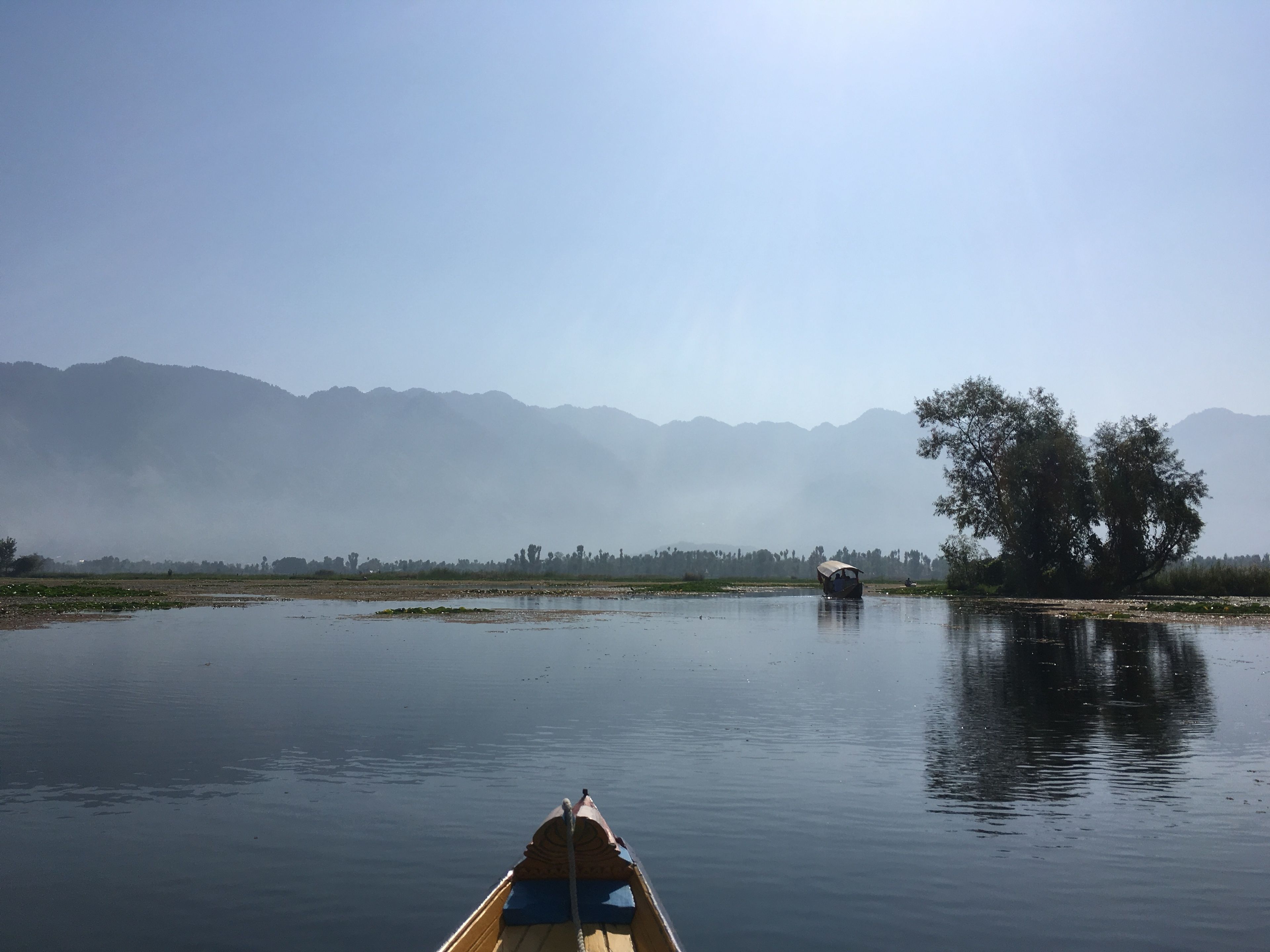 A calm river with a boat in the foreground and a distant boat on the river.