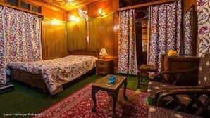 A cozy room with a bed, a small table, a chair, and a patterned curtain. - Lily of Nageen (Srinagar)
