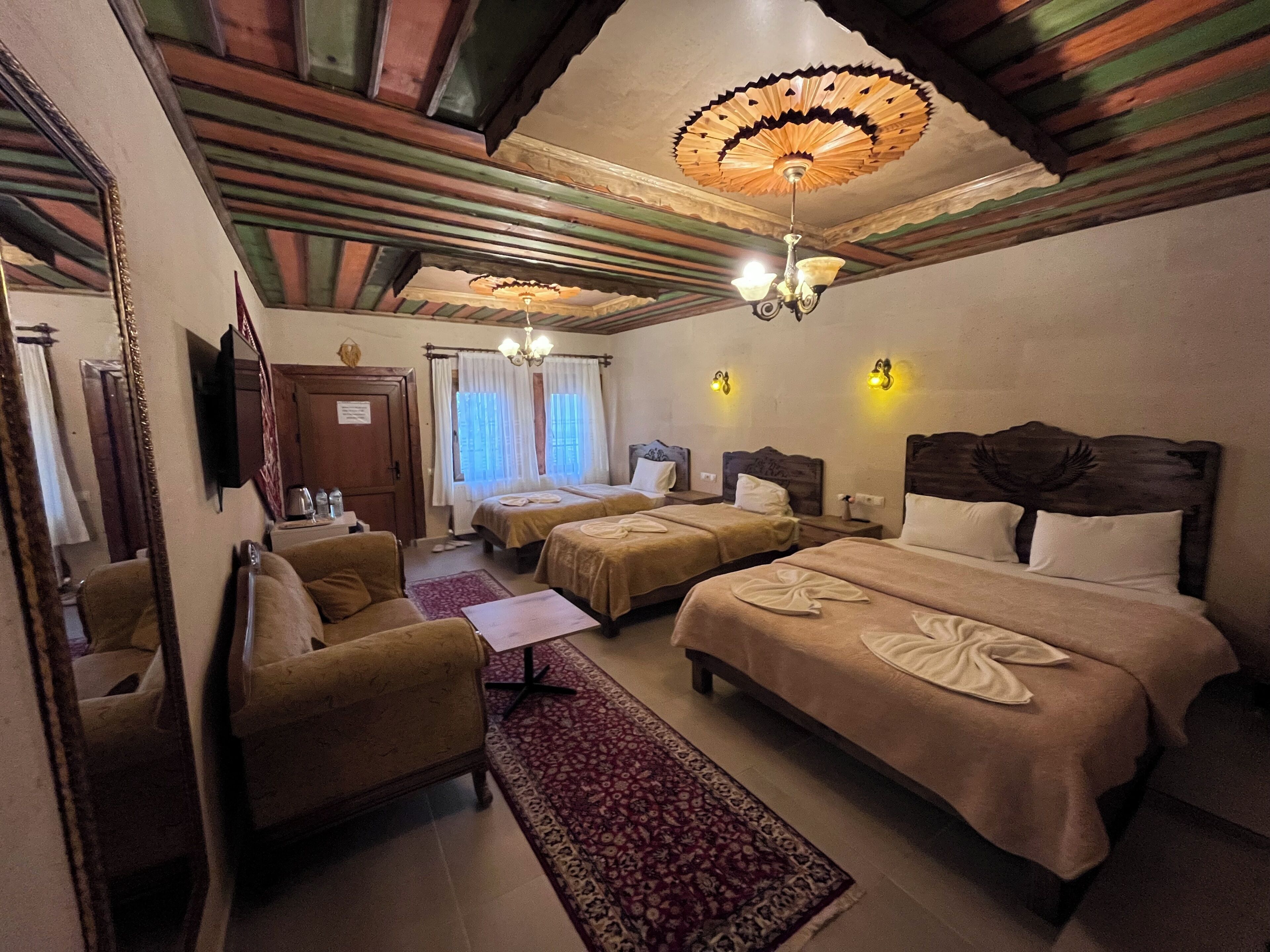 Une chambre d’hôtel avec deux lits, un canapé, une télévision et un lustre.