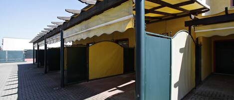 Una zona exterior coberta amb terra de rajola, una reixa metàl·lica i una paret groga.