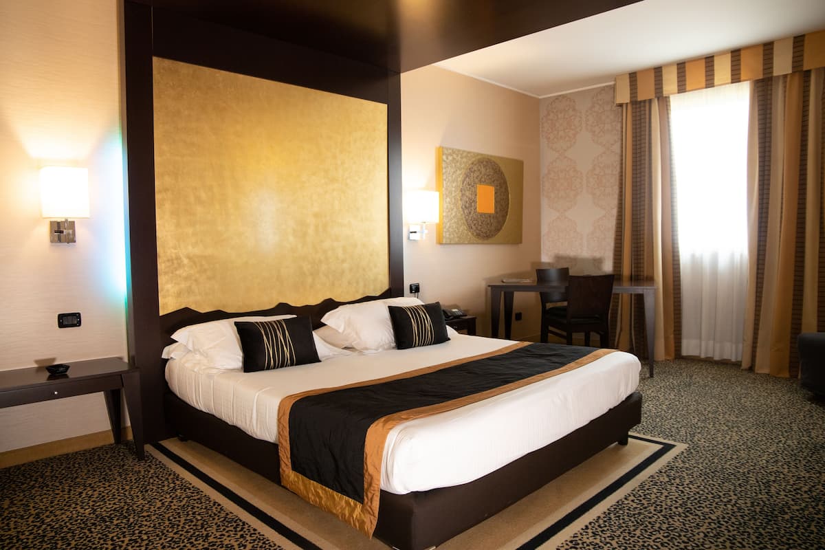 A hotel room with a large bed, a desk, and a chair.