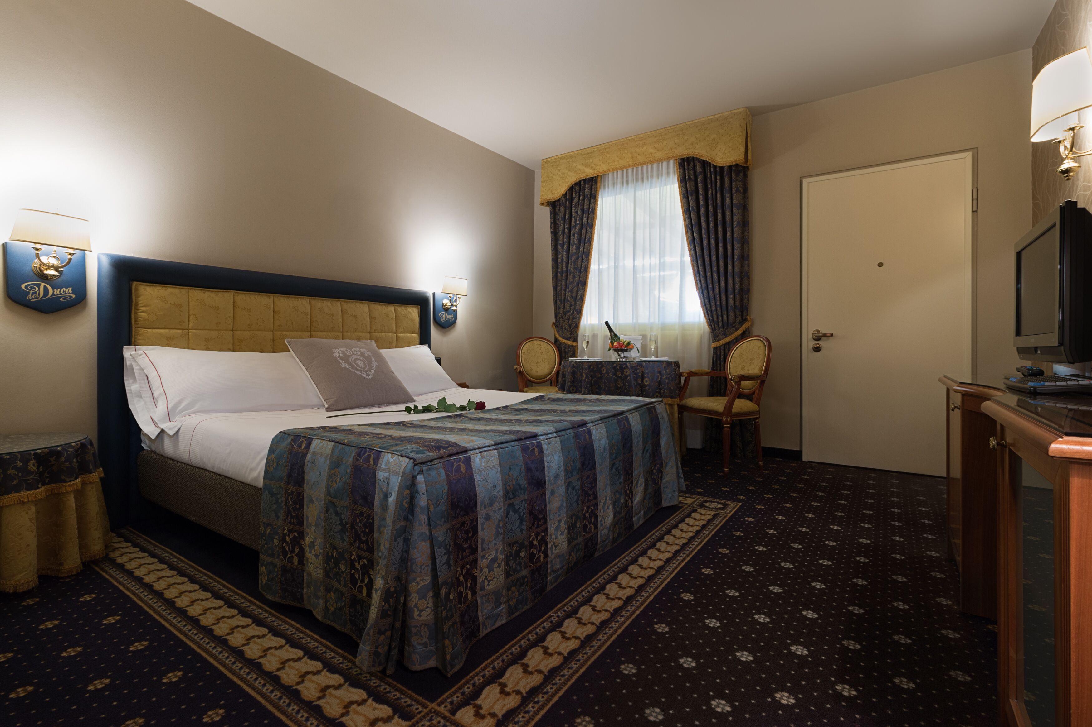 A hotel room with a bed, a television, a chair, and a desk.