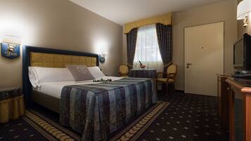 A hotel room with a bed, a television, a chair, and a desk.