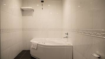 Un baño moderno con una bañera independiente, paredes de azulejos blancos y suelo de baldosas negras.