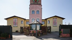 A hotel with a central tower, a gated entrance, and potted plants. - Hotel Motel Del Duca (Cava Manara)
