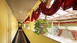 A hotel corridor with yellow walls, a patterned carpet, and red drapes. - Hotel Motel Del Duca (Cava Manara)