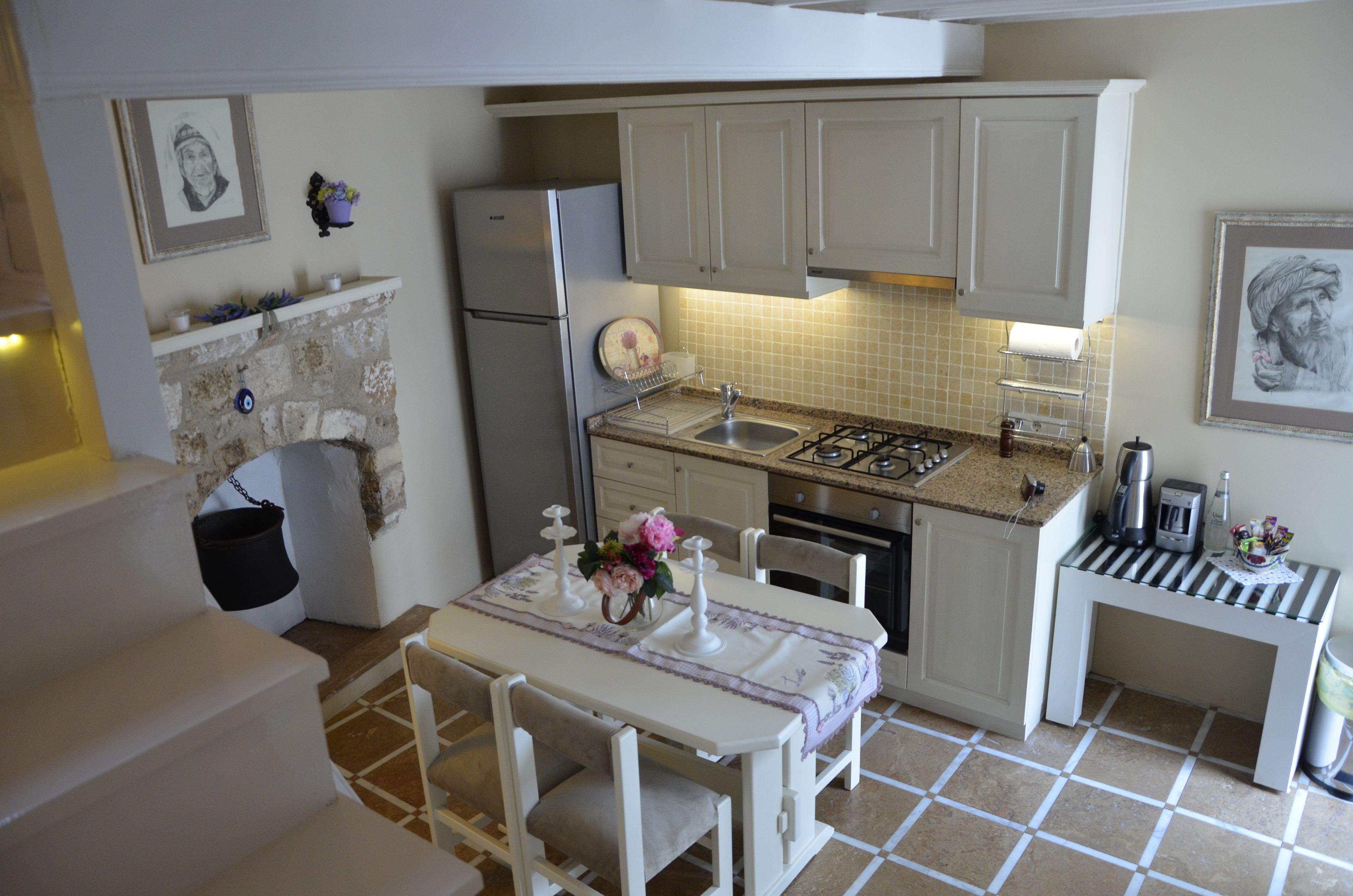 A compact kitchen with white cabinets, a gas stove, a sink, and a dining area with a table and chairs.