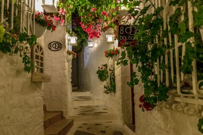 Une ruelle étroite aux murs de pierre, avec un escalier menant à une porte portant le numéro « 808 ».