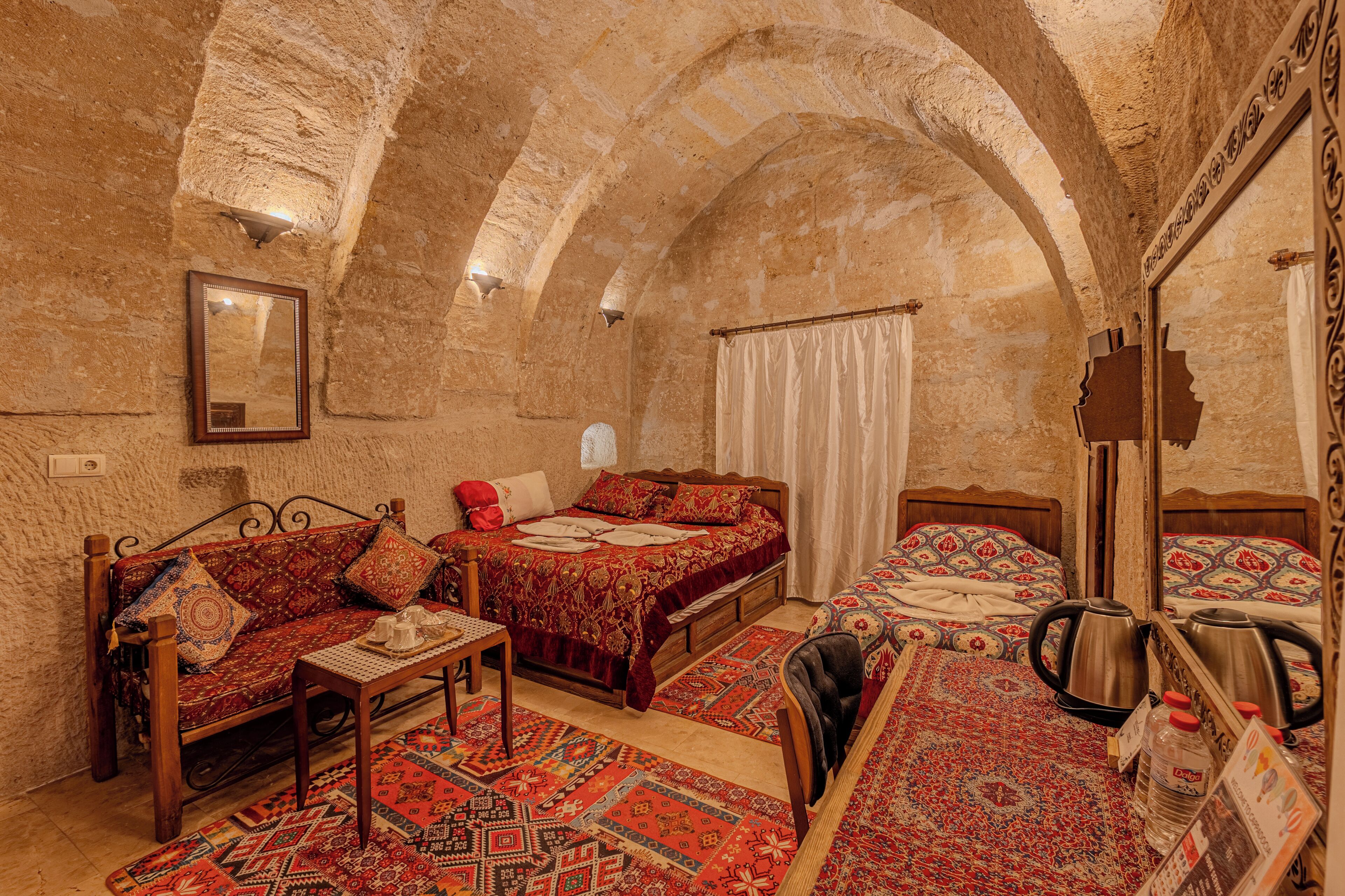 A traditional room with two beds, a sofa, and a table.