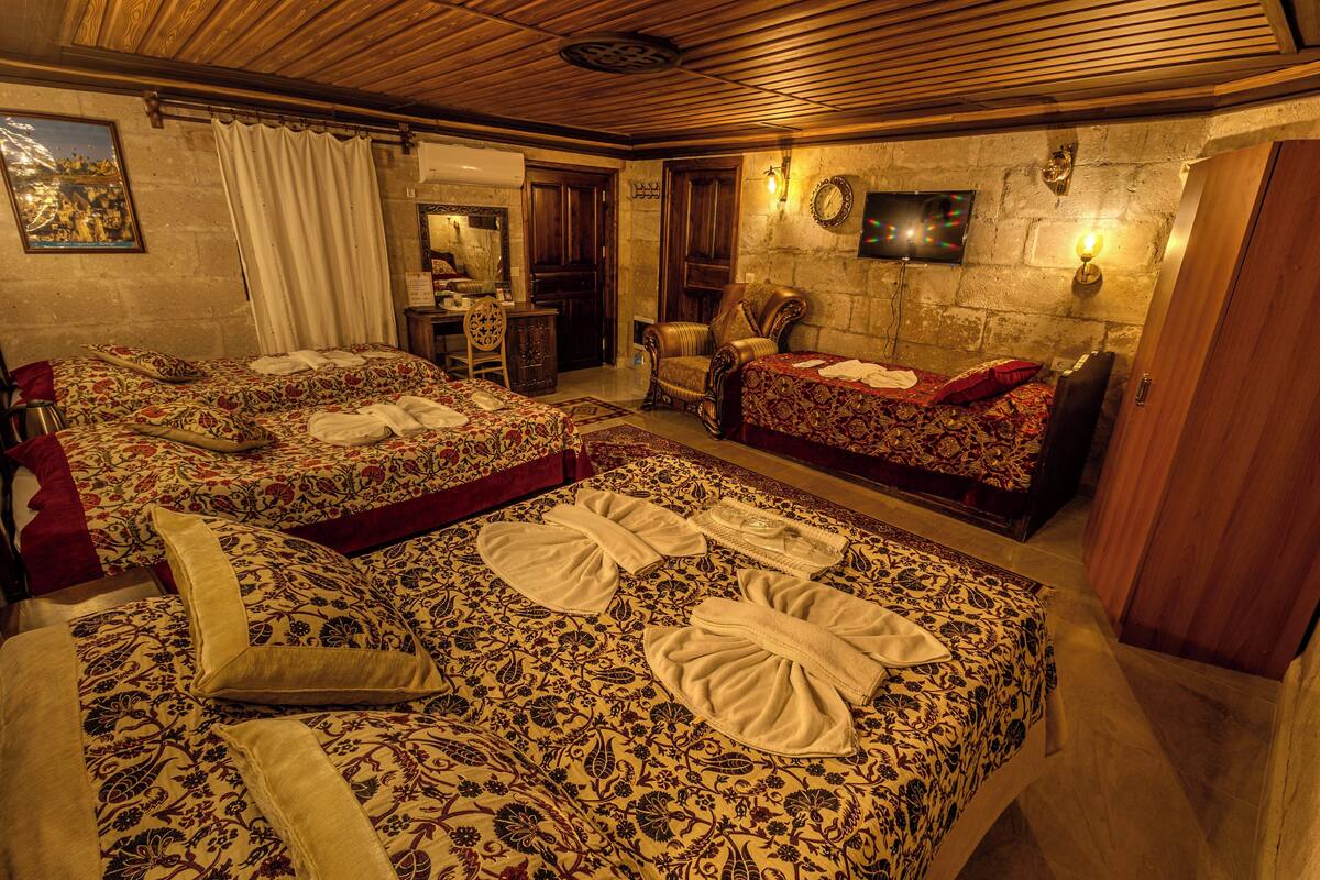 Quarto de hotel com duas camas, área de estar e televisão.