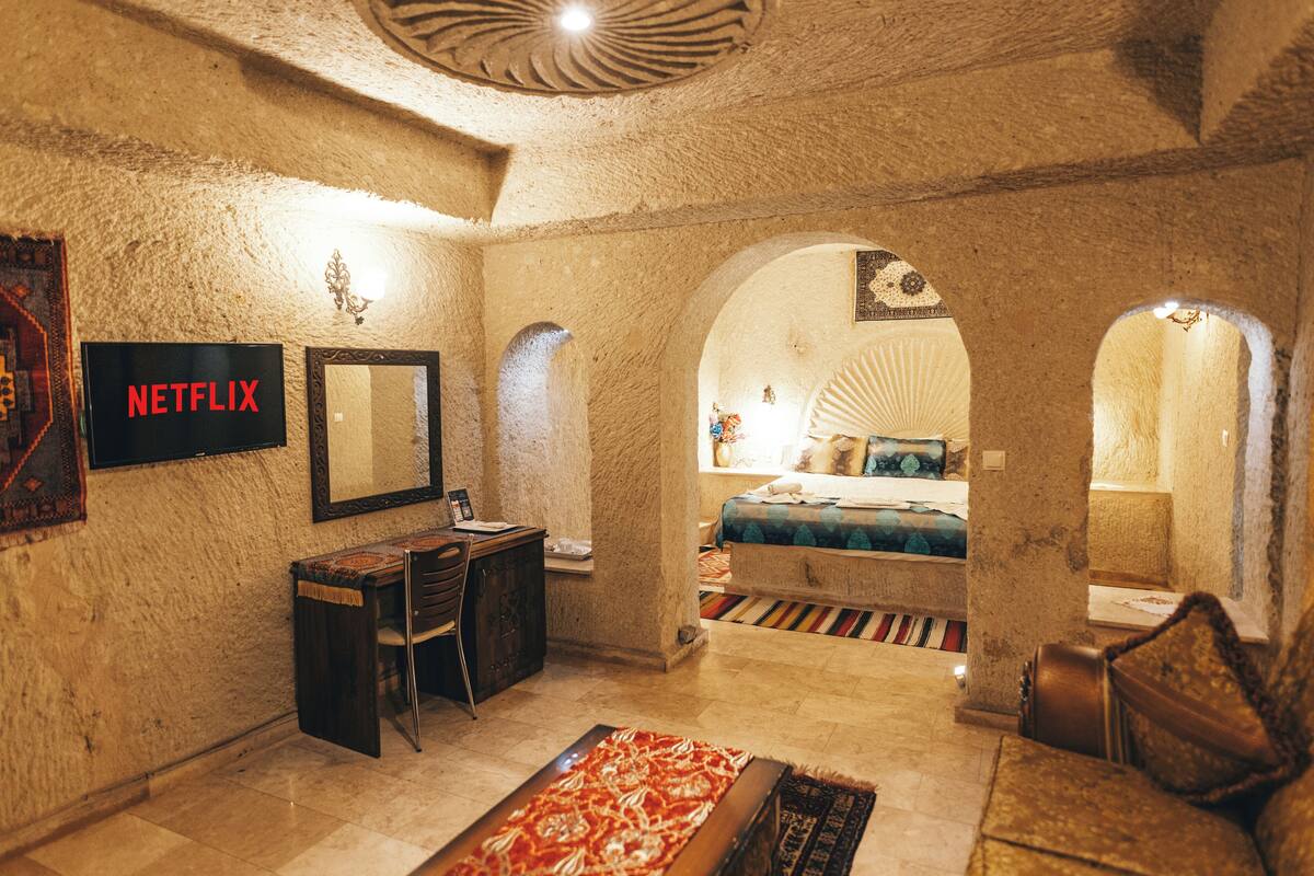 Um quarto acolhedor com uma mesa, uma cama e uma grande porta em arco que dá para outro espaço.