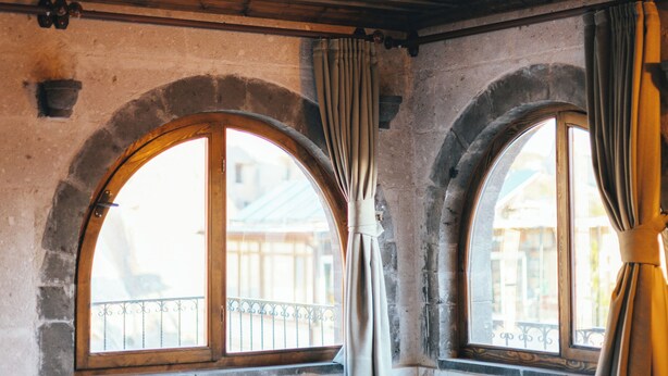 Una stanza con una vasca da bagno a forma di botte, due finestre ad arco con tende e un soffitto decorato.