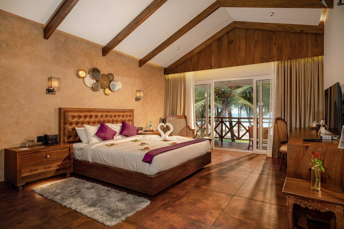 A spacious bedroom with a large bed, wooden headboard, and a balcony with a view.