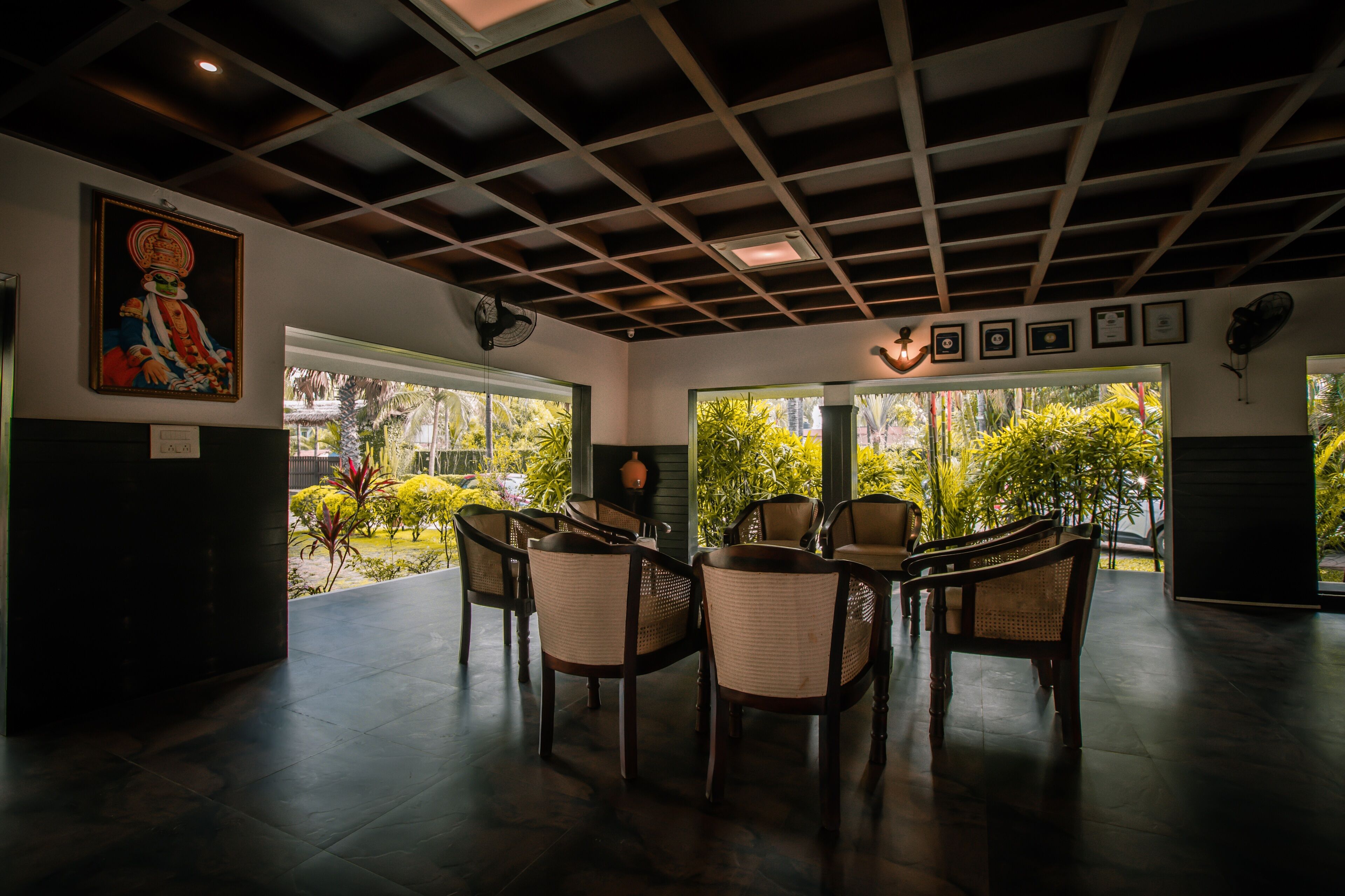 A room with a ceiling fan, a painting, and a view of greenery outside.