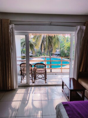 A room with a view of a pool, two wicker chairs, a wooden table, and a sofa. - Malabar Ocean Front Resort & Spa (Hosdurg)