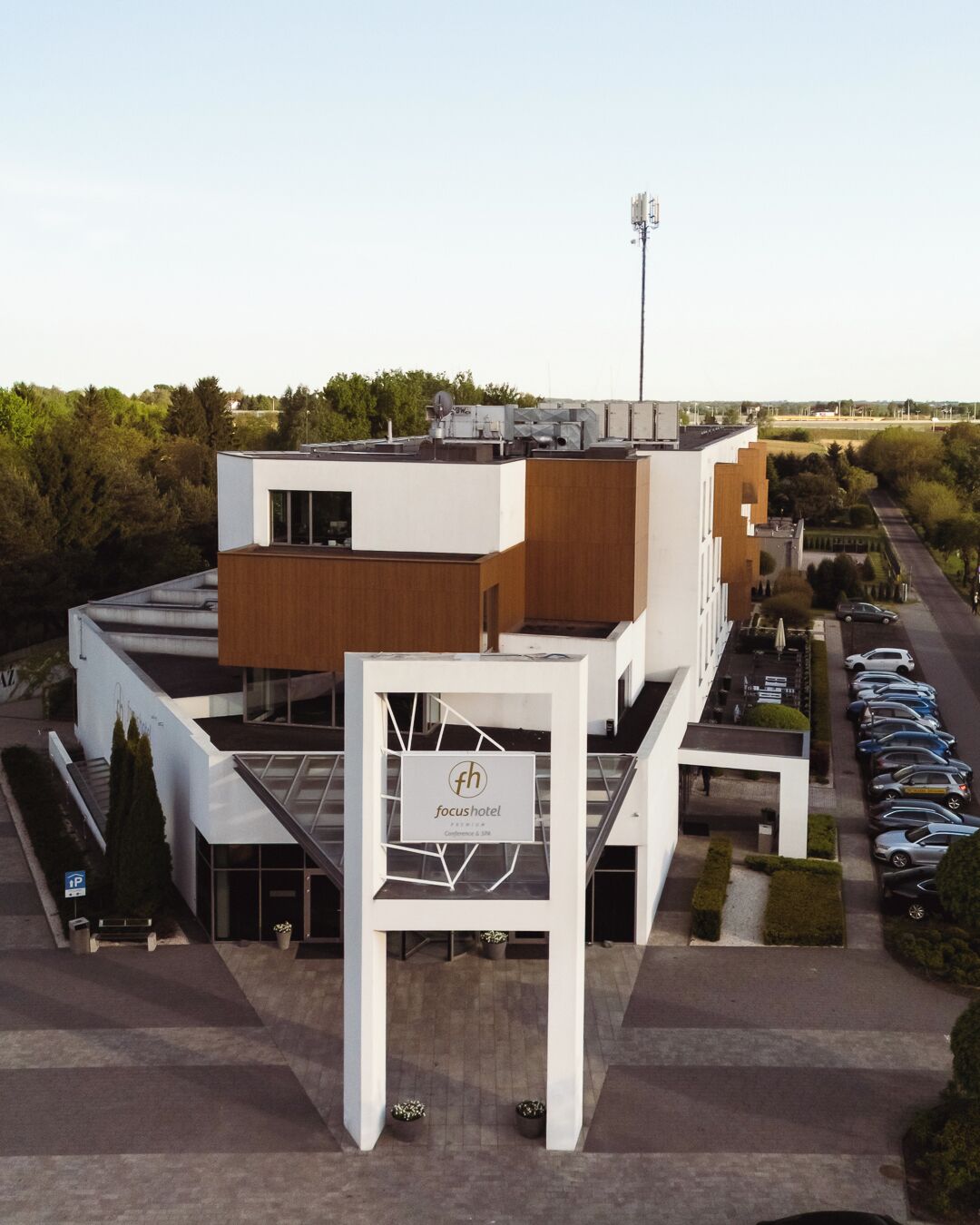 Un hotel moderno con un letrero llamativo, un estacionamiento y una vista despejada del entorno.