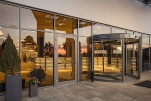 A modern hotel entrance with a revolving door, glass doors, and a reception area visible through the glass. - Focus Hotel Premium Lublin Conference & SPA (gmina Jastków)