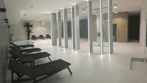 A modern indoor swimming pool area with lounge chairs, a hot tub, and a wooden wall. - Focus Hotel Premium Lublin Conference & SPA (gmina Jastków)