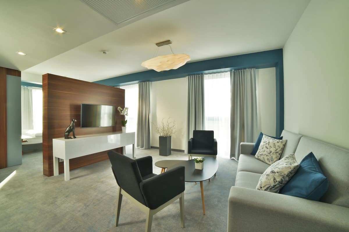 Uma sala de estar moderna com uma televisão de tela plana, um sofá, duas poltronas, uma mesa de centro e uma parede de destaque em madeira.